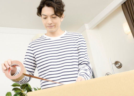 段ボールをガムテープで塞ぐ男性